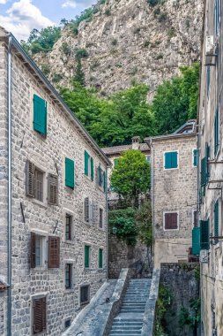 Karadağ 'ın Kotor kentinde, tahta kepenkleri ve dik taş basamakları olan taş evlerin yer aldığı tuhaf dar bir cadde. Yeşil kepenkler ve çevreleyen dağ eski kasaba mimarisine manzaralı bir cazibe katıyor.