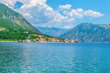 Karadağ 'ın Prcanj kentinin, dağlarla Kotor Körfezi' nin mavi suları arasında kurulmuş büyüleyici binalarıyla manzaralı bir manzarası var. Manzarası Montenegros 'un doğal güzelliğini vurguluyor.