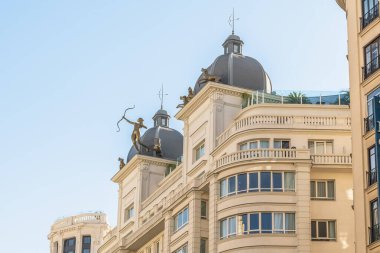 Gran Via 'da bulunan binanın üst kısmı, Madrid, İspanya. Çatı, okçu heykelleri ve dekoratif unsurlarla süslenmiş. Bina mimarisine çarpıcı bir sanatsal dokunuş katıyor.