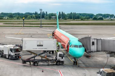 Kyiv, Ukrayna - 16 Haziran 2021: Boryspil Uluslararası Havalimanı 'nda WindRose uçağının bakımı. Pistin etrafındaki uçak ve servis kamyonlarına giden teleskopik yolcu köprüsü.
