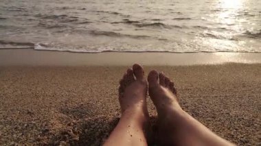Dalgalar içeri girerken kumlu bir sahilde çıplak ayaklar. 4K video, 36 saniye. Yaz, dinlenme ya da tatil temaları için mükemmel.