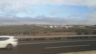 İspanya 'da bir sonbahar günü Girona' ya giden bir otobüs penceresinden manzarayı izliyoruz. Video 31 saniye. Yuvarlanan tepeler, tarlalar ve köyler bulutlu bir gökyüzünün altından geçer.