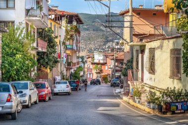 Türkiye 'nin Alanya kentinde renkli evler ve park halindeki arabalarla dolu güneşli bir iskan caddesi. Yerel halk sessiz caddede yürürken Türk bayrağı balkonlardan birinde asılı duruyor. Alanya, Türkiye - 24 Ekim 2020