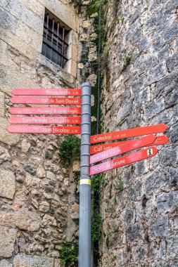 Girona 'nın eski bir kasabasında Banys Arapları, Sant Feliu Katedrali ve antik taş duvarlara karşı Arkeolojik Yürüyüş gibi turistik yerleri gösteren bir tabela. Katalan dilinde tarihi yön bulma işaretleri. Girona, İspanya - 28 Kasım 2021
