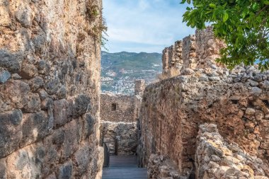 Alanya Kalesi 'nin antik taş duvarları çevresindeki dağları gören dar bir geçit oluşturur. Türkiye 'deki bu tarihi kale bölgenin zengin mimari mirasını yansıtıyor