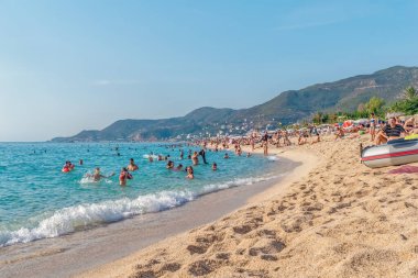 Güneşli bir yaz gününde Alanya, Türkiye 'deki Kleopatra Sahili' nde deniz ve kumların keyfini çıkarıyordu. Arka plandaki dağlar kıyı şeridinin manzaralı güzelliğini artırıyor. Alanya, Türkiye - 24 Ekim 2020
