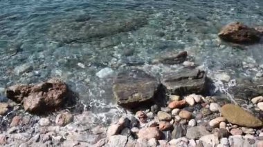 Türkiye 'nin Alanya kentinde kıyıya vuran dalgalarla kayalık bir deniz manzarası. 30 saniyelik video. Kristal berrak su, kayalık deniz tabanını ve mavinin çeşitli tonlarını gösteriyor.