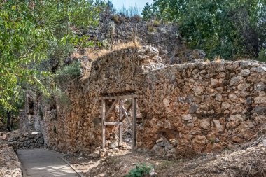 Türkiye 'nin Alanya Şatosu' ndaki antik taş duvarlardan geçen ve kısmen tahta kirişlerle desteklenen bir patika. Bu tarihi alan kırsal mimariyle çevreleyen yeşilliği harmanlıyor.