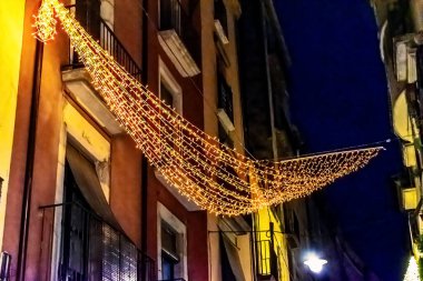 Işıldayan sicim lambaları Girona 'nın eski şehri İspanya' da dar sokakları aydınlatıyordu. Ortaçağ binaları arasında asılı sıcak altın renkli çelenkler derin mavi gökyüzüne karşı büyülü bir festival atmosferi yaratır.