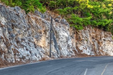 Türkiye 'deki Alanya Şatosu yakınlarındaki kayalık bir kayalık yol boyunca çam ağaçlarıyla çevrili. Doğal manzara asfalt yol ile harmanlanarak ziyaretçiler için manzaralı bir rota oluşturuyor.