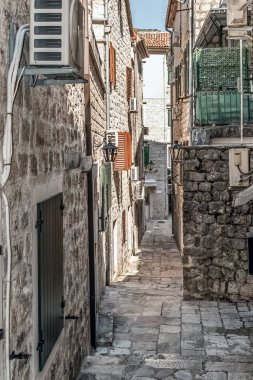 Karadağ 'ın eski Kotor kentinde, geleneksel binalar ve klima üniteleriyle dolu dar bir ara sokak. Bu huzurlu manzara, tarihi kasabanın büyüleyici mimarisini ve sessiz sokaklarını yansıtıyor.
