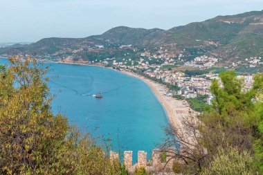Kleopatra Sahili ve Türkiye 'nin Alanya kentindeki dağların manzarası. Berrak mavi su ve kıyı şeridi yemyeşil ile güzel bir zıtlık yaratır.