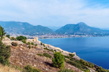 Alanya Şatosu 'nun manzarası Akdeniz' e doğru uzanırken, kasaba ve çevresindeki dağlar Türkiye 'nin arka planında yer alıyor. Tarihi mimari ve doğal güzelliğin pitoresk bir birleşimi.