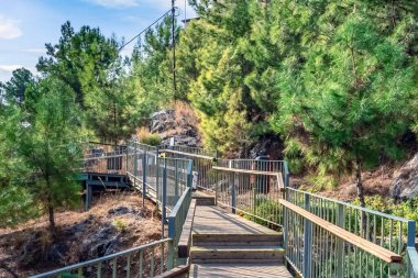 Türkiye 'nin Alanya kentindeki kayalık bir yarımadada, tarihi Alanya Kalesi kalesine doğru uzanan sakin bir ahşap geçit. Yol, ziyaretçiler için manzaralı ve huzurlu bir yol sağlayan yemyeşil ağaçlarla çevrili.