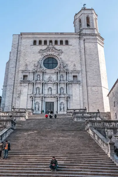 Santa Maria Katedrali etkileyici Barok görünüşü ve muazzam merdivenleri ile. Heykeller ve dekoratif unsurlarla girişe giden büyük taş basamakların görüntüsü. Ünlü 91 basamağa tırmanan ziyaretçiler. Girona, İspanya - 28 Kasım 2021