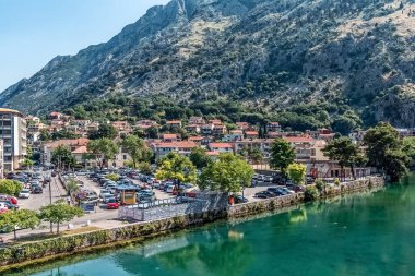 Karadağ 'ın Kotor kenti, dağlarla kıyı şeridi park alanı arasında yer alıyor. Evler ve arabalar yemyeşil ve engebeli tepelerle çerçevelenmiş. Kotor, Karadağ - 18 Haziran 2021