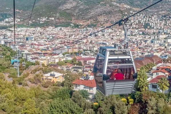 Türkiye 'nin Alanya kentinde, Akdeniz kıyısı ve çevresindeki tepelerin panoramik manzaralı bir teleferik gezisi. Teleferik şehrin manzarasına benzersiz bir bakış açısı sunuyor.