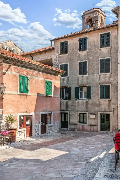 Karadağ 'ın Kotor kentinin sakin bir köşesinde tarihi taş binalar, yeşil kepenkler ve küçük bir kafe bulunuyor. Mimari, bu Akdeniz şehrindeki eski kasabanın cazibesini ve huzurlu atmosferini yansıtıyor.