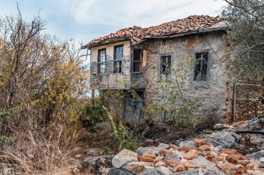 Türkiye 'nin Alanya Şatosu' nun kayalık tepelerindeki eski, terk edilmiş taş ev. Etrafı ağaçlar ve çalılarla çevrili. Tarihin unutulmuş bir parçası doğayla harmanlanmış.