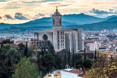 Majestic Girona Katedrali bu tarihi Katalan şehrinin tepe çizgisine dramatik bir dağ zeminiyle hakim. İspanya. Ortaçağ Gotik katedralinin çarpıcı manzarası şehir manzarası ve Pireneler ile dolu yemyeşil alanlar ile çevrili.