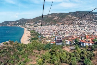 Alanya Teleferik teleferiğinden nefes kesici bir manzara, Kleopatra Sahili ve Türkiye 'nin Alanya kentinin çarpıcı manzarasını gözler önüne seriyor. Canlı kıyı şeridi ve yeşil tepeler manzaranın güzelliğini arttırır.