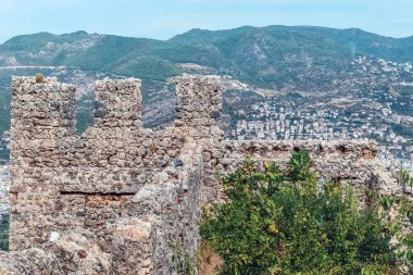 Türkiye 'deki Alanya Şatosu' nun antik taş duvarları şehrin arka planına ve etrafındaki dağlara karşı yükseliyor. Kale, Akdeniz kıyı şeridini ve aşağıdaki şehri panoramik bir şekilde gösteriyor.