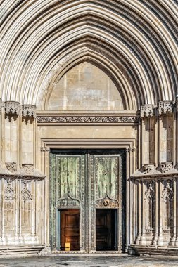 Girona Katedrali 'nin şaşaalı yeşil kapıları ve İspanya' nın özenle döşenmiş taş kemer yolu ile süslü Gotik girişi. Kadim taş kapı, birden fazla kaburgalı kemer, karmaşık oymalar ve büyük sivri kemerli kemerin altındaki bronz kapı çivileri içerir.