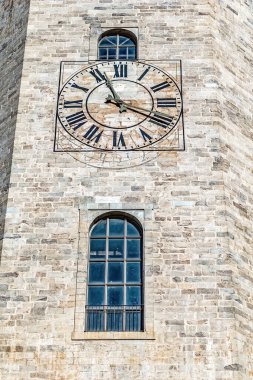 Girona Katedrali 'ndeki tarihi saat kulesi büyük Roma rakamlı saat yüzlü ve kemerli pencereli İspanya. Kadim taş ustalığı, yıpranmış kireçtaşı cephesinde belirgin bir şekilde gösterilen ortaçağ zanaatkarlığını sergiliyor.