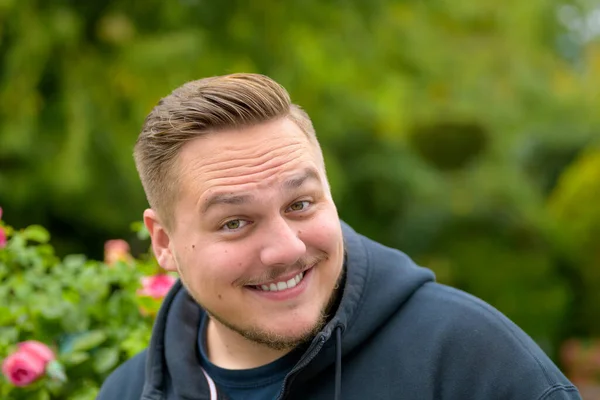 Genç Adam Sonbaharda Bahçenin Önünde Yaramaz Bir Gülümsemeyle Kameraya Bakar — Stok fotoğraf
