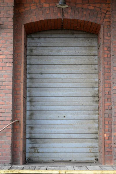 Gray roller door of an old building with a brown brick wall