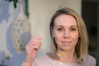 Gorgeous attractive blond woman in her fourties smiling softly at the camera