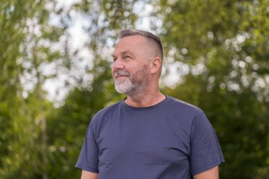 Intense senior man looking aside with an strong expression outdoors in a park