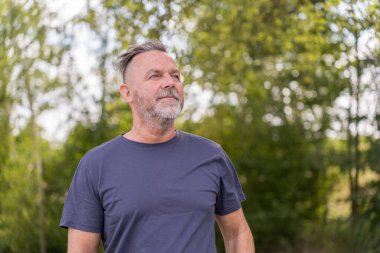 Intense senior man looking aside with an strong expression outdoors in a park