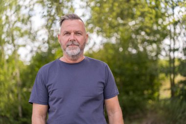 Intense senior man looking into the camera with an strong expression outdoors in a park