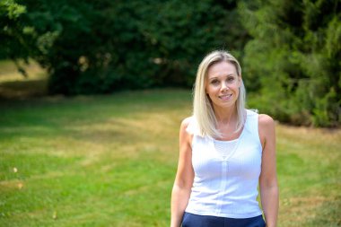 Attractive middle aged blond woman with long blond hair walking in a park in summer