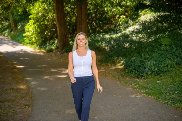 Happy Healthy Blond Woman Strolling Shady Lane Approaching Camera Smile — Stock Photo, Image