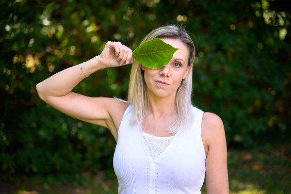 Attractive Blond Woman Covering One Eye Green Leaf Conceptual Image — Stockfoto