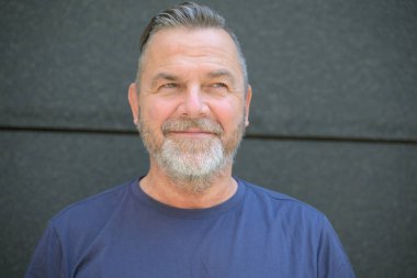 Mutlu, hayat dolu, sakallı, orta yaşlı bir adam başı ve omuzlarında bir gülümsemeyle yan yana duran bir portre.