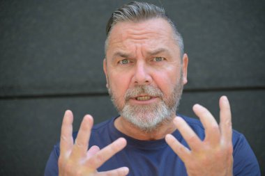 Münakaşacı adam kameraya parmağını sallayarak bir noktaya parmak basıyor.