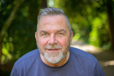 Son sınıf öğrencisi, dışarıda parkta, yüzünde beklenen ifadeyle kameraya bakıyor.