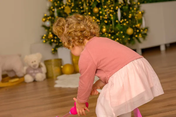 Маленькая Девочка Играет Своим Подарком Перед Украшенной Елкой Рождество — стоковое фото