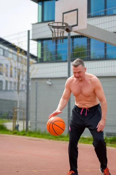 黒のスポーツの短いドリブルで中年の恥知らずの男の完全な体の特性とスポーツフィールド上のバスケットボールを見下ろします — ストック写真