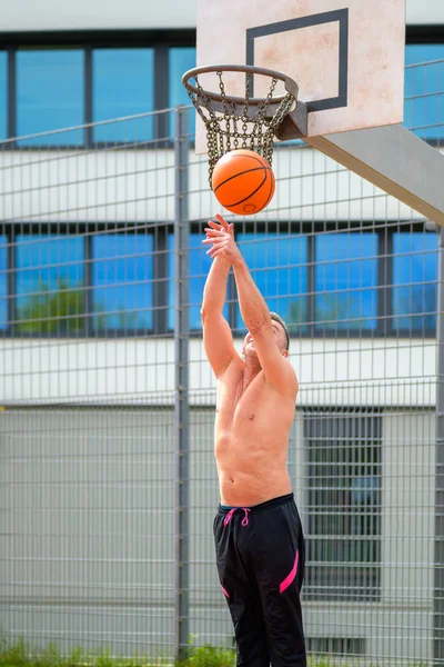 穿着黑色运动短裤的中年人在运动场打篮球的时候扔篮子 — 图库照片
