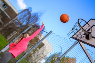 Spor sahasında basketbol oynarken hoplayıp zıplayan çekici sarışın kadın.