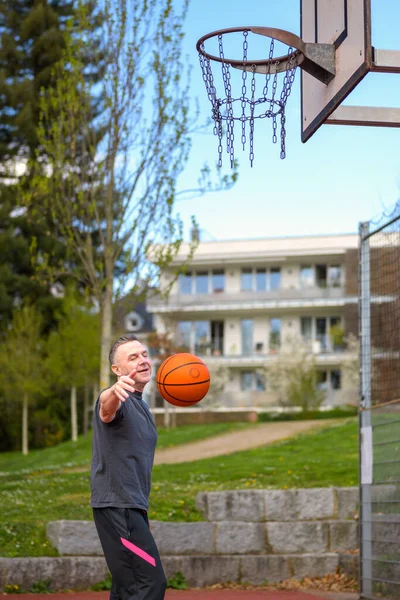 身穿黑色运动短裤的中年男子把篮球集中在一个运动场上 — 图库照片
