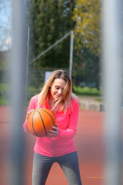 Atrakcyjna Blondynka Uśmiechnięta Kobieta Dribbles Skoncentrowała Koszykówkę Boisku Sportowym — Zdjęcie stockowe