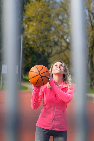 迷人的金发女人正要跳起来 手里拿着篮球在运动场上跳 — 图库照片