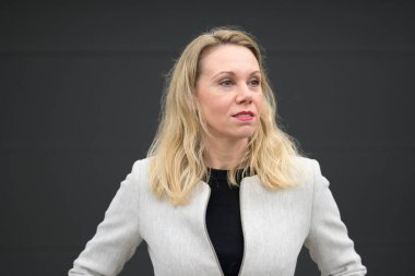 Orta yaşlı kadın yumuşak bir gülümsemeyle yan yana bakar.