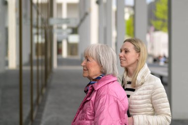 Bir anne ve kızın dikilip bir alışveriş penceresine bakması.