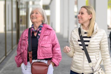 Anne ve kızı alışveriş merkezinde alışveriş yaparken ayakta dikilip bir dükkâna bakıyorlar.